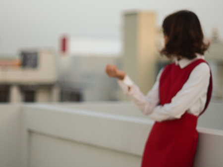 Blurred abstract background of standing Asian woman in red dress, thinking woman, business concept.の写真素材