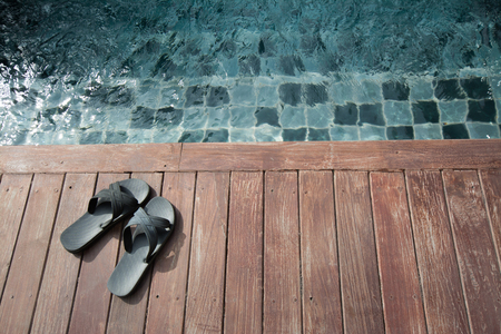 Black sandals on the wooden background near the swimming pool, slipper on the wooden floor.の写真素材