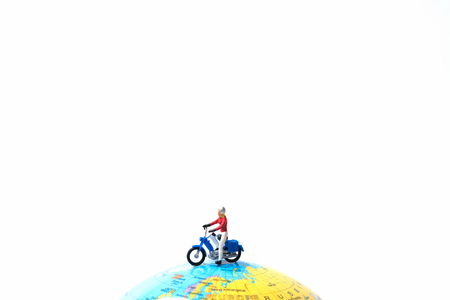 Tiny miniature model of the man is riding the motorbike or motorcycle on globe using as travelling, journey, travel to destication background concept.の写真素材