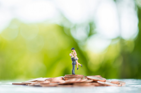 The man pick the woman up on the pile of coins using as growing together, teamwork, partnership and...