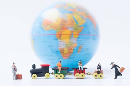 Tiny miniature model of travelers with luggage are sitting on the train with globe background using as travelling, journey, travel to destination background concept.の写真素材