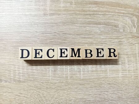 Wooden block is arranged the word DECEMBER in black font on wooden background with the space for your text.の写真素材