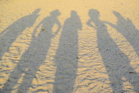 A group of happy travelers shadow over the beach sand at sunset time using for texture background.の写真素材