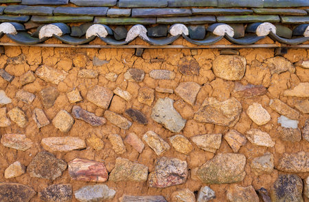 Old stone wall and tiled roof of a house. Background.の写真素材