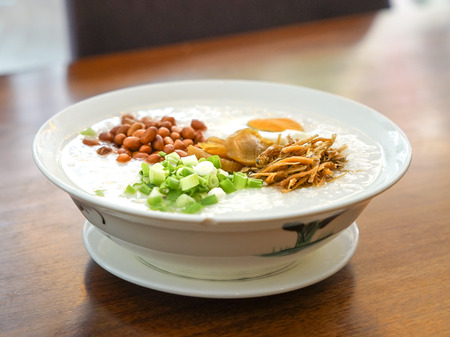 Rice porridge with peanuts, spring onion, vegetables and fried anchovies toppingsの写真素材