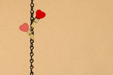 Love concept: Two red and pink clips with heart shape on a steel chainの写真素材