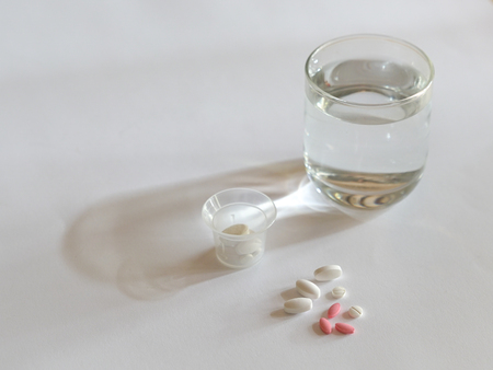 Heealth concept: pills or medicine with a glass of water on white backgroundの写真素材