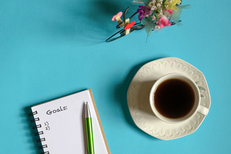 Top view goals list with memo pad, cup of coffee and pen on pastel blue backgroundの写真素材
