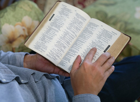 Reading the bible, a hand on a page of an open bibleの写真素材