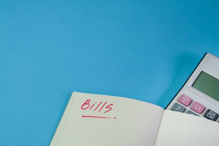 Bills. Notepad with calculator on top of blue color table. Copy space.の写真素材