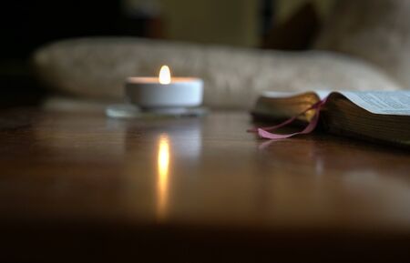 Open bible with burning candle on the table. Cosy home environment.の写真素材