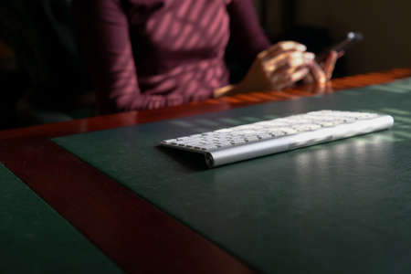 Woman reading her cell phone with keybaord at the tabletop. Copy space.の写真素材