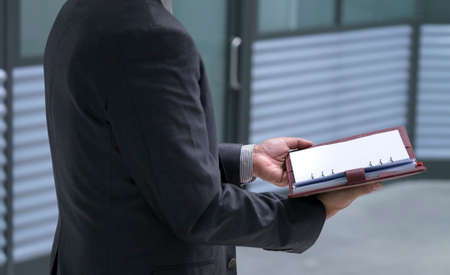 Businessman holding and open up diary or planner in his hands. Meeting or appointment concept.の写真素材