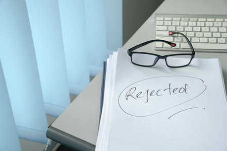 Handwritten word, Rejected on top of pile of documents on tableの写真素材