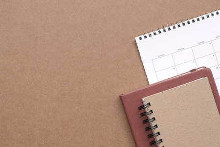 Notebooks and calendar on brown color table. Top view. Copy space.の写真素材