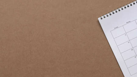 White calendar on brown cardboard paper, copy space. Business meeting, planner and reminder concept.の写真素材