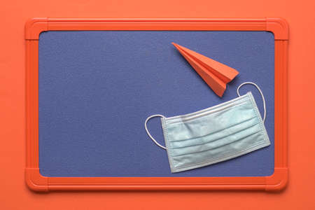 Face mask on top of notice board with paper plane. Copy space.