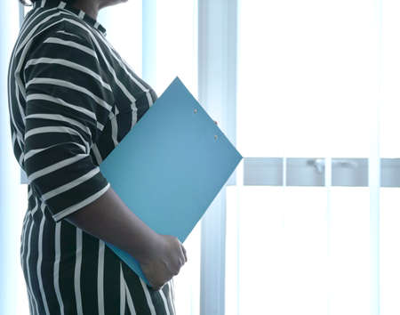 Closeup view of woman's hand holding aa blue clipboard. Copy space.