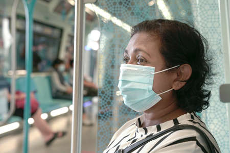 Woman commuter wearing face mask inside train. Travel during pandemic concept.