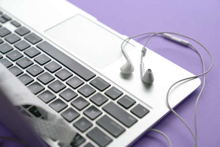 Ear phones on top of computer laptop. Purple table top.の写真素材