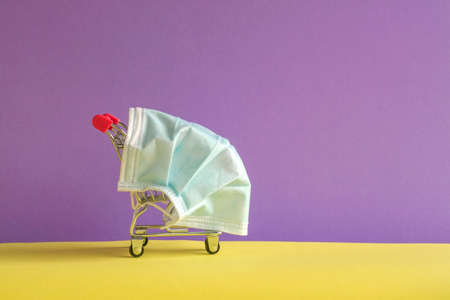 Shopping cart with protective medical mask. Copy space. Safe and online shopping on quarantine concept.の写真素材