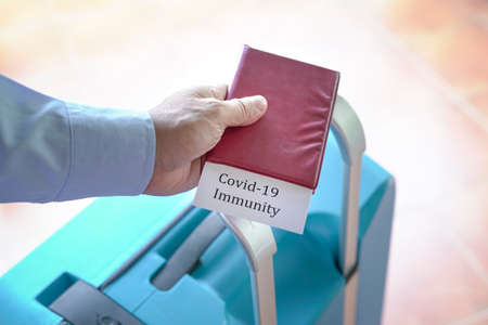Traveler holding a passport with Covid-19 Immunity label inside.