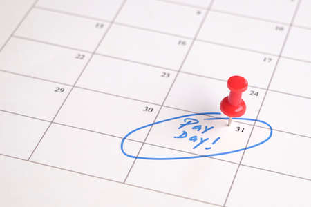 Red pin on calendar with words, pay day written. Salary reminder concept.の写真素材