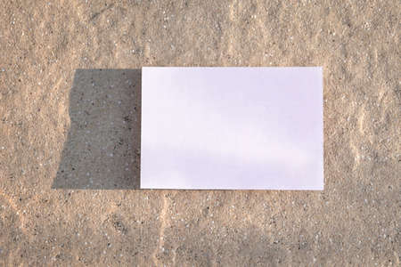 Empty white paper or card wiht shadows on beige rustic surface. Marketing, business card or email newsletter concept.の写真素材