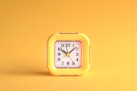 Yellow clock on yellow background. Center of the frame.