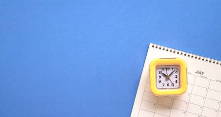 Yellow clock on top of calendar or planner. Planning for meeting or travel concept. Copy space.の写真素材