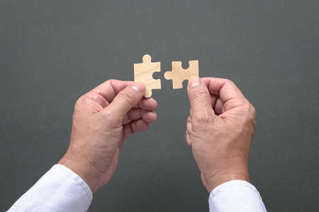 Two hands holding jigzaw puzzles, business matching, finding the right fit concept.