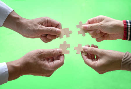 Business people assembling jigzaw puzzle. Close up shot. Concept of cooperation, teamwork and...