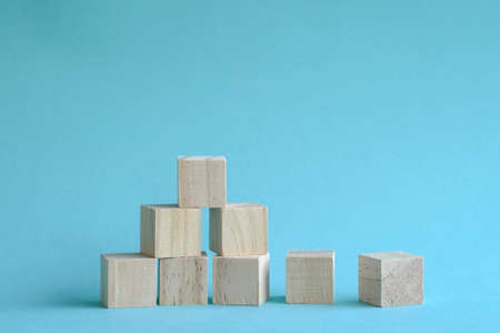 Wooden blocks stacking as a pyramid staircase on blue background. Success and growth concept.の写真素材