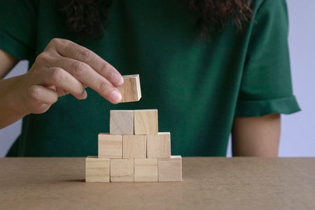 Woman hand arranging wood block stacking as step stair. Business growth or success concept.の写真素材