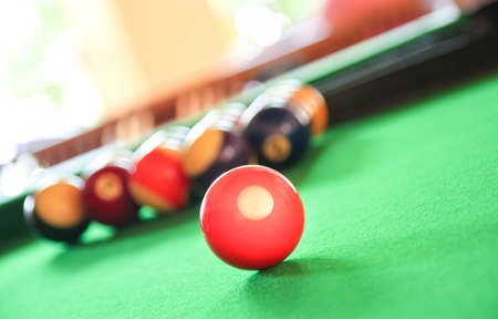 Red ball stand out from the rest of billiard balls at the background. Stand out or leadership...
