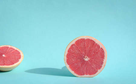 Fresh cut grapefruit on sunlight with harsh shadows on blue pastel background. Copy space.の写真素材