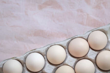 Box of white eggs on beige color background. Top view, copy space.