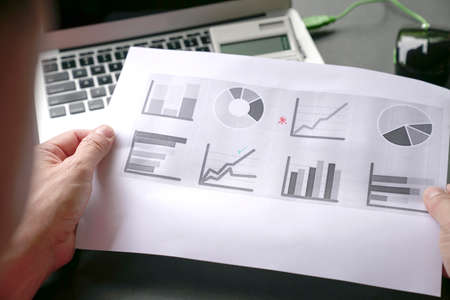 Man holding and analyzing charts and graphs. Investment portfolio concept.の写真素材