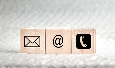 Website and internet contact us page concept with black icons on wood cubes.の写真素材