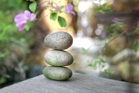 Stones stacked on top of each other, surrounded by nature flowers and mini waterfall.の写真素材