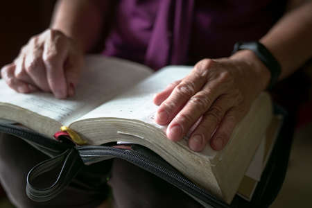 Elderly woman wrinkled hand on an open book. Close up view.の写真素材
