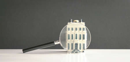 Magnifying glass on mini building, isolated. Search for property concept.