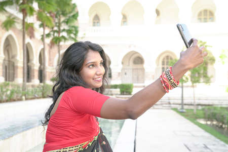Asian Indian ethnic woman using smartphone to take self portrait or video chat.