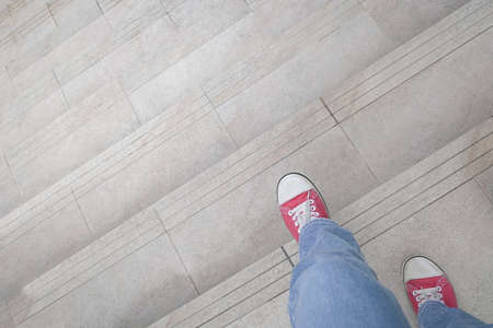 Close up view of woman in red shoes walking down the stairs. Stepping down or out concept.の写真素材