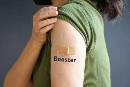 Close up view of woman arm with bandage and the word Booster - getting vaccinated immunity. Inoculation, vaccination, vaccinated patient concept.の写真素材