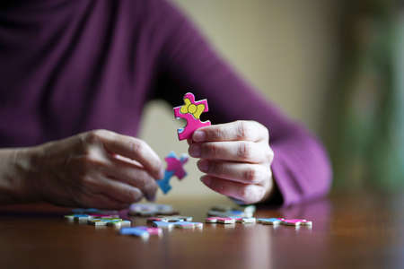 Close up view of woman playing jigsaw puzzle. Indoor game or activity concept.の写真素材