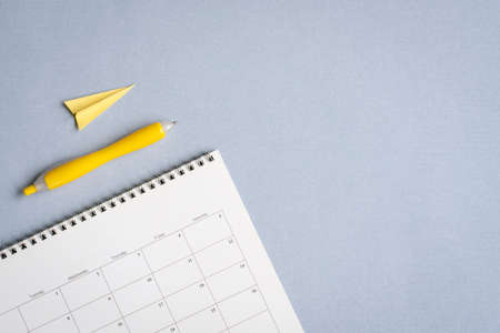 Flat lay of calendar with pen and paper plane with copy space, Travel vacation planning concept.