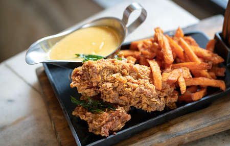 Chicken chop with chips and salted egg sauce on a grill pan.