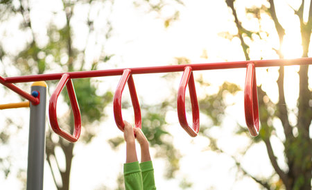 Kid playing on a children playground equipment, outdoor. Close up view of kid's hands on triangle monkey bars.の写真素材