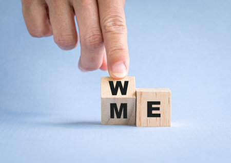 Fingers flip wooden cube with word me to we. Teamwork concept.の写真素材